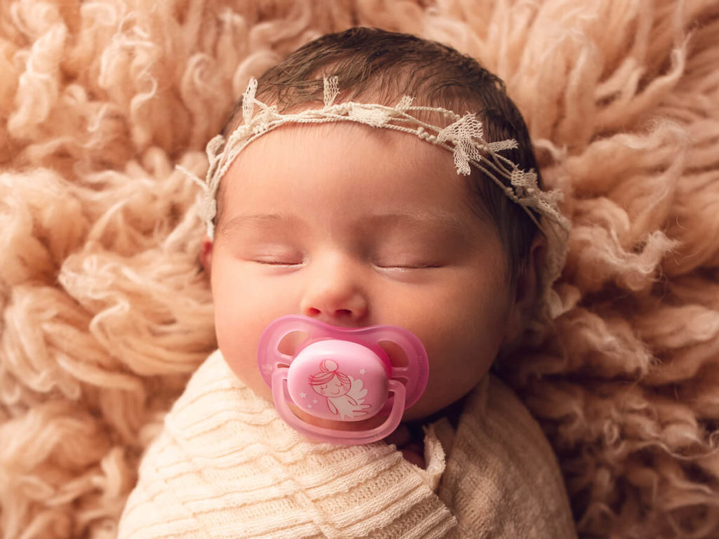 Newborn baby using a dummy at a photo session